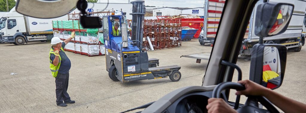 A employee in a yard directing traffic following Lorry Banksman Training Course