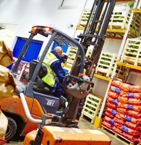 A employee using a counterbalance forklift truck in a warehouse after for forklift truck training