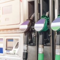 Fuel dispensing nozzles with colored handles at a petrol station.