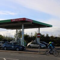 Petrol station with a 24-hour service sign and vehicles at the pumps.