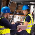 Forklift instructor showing a delegate who is sitting on a forklift, in a warehouse in Norfolk.