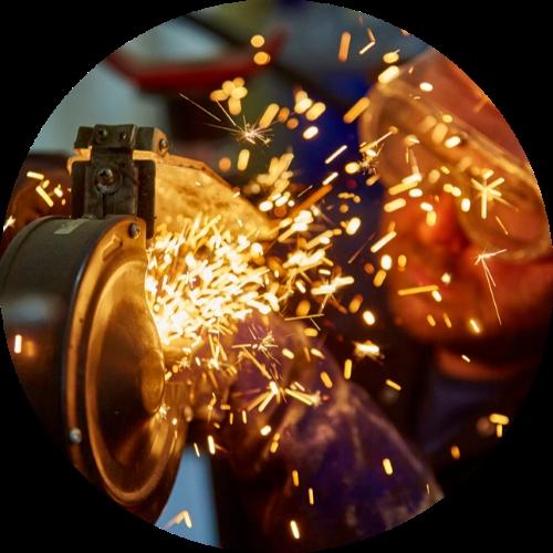Abrasive wheel grinding metal sends a burst of bright orange sparks across the workshop air.