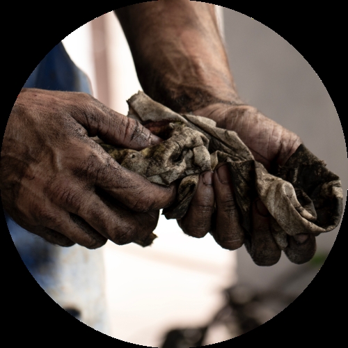Rough, dirt-covered hands squeeze a stained rag while cleaning closely after heavy manual work.